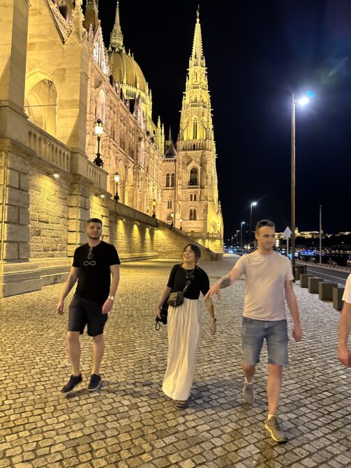 Three Resource Guru colleagues walking by the Hungarian Parliament Building in Budapest at night.