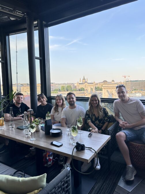 Six members of Resource Guru's team drinking cocktails on Leo Rooftop in Budapest.