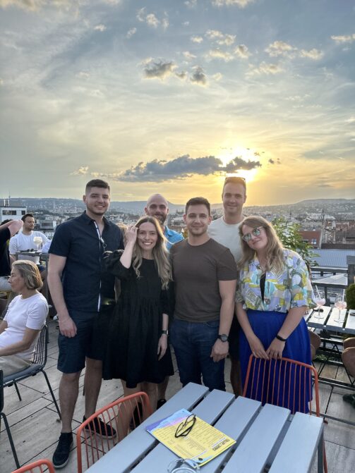 Six of Resource Guru's team on a rooftop at golden hour in Budapest.