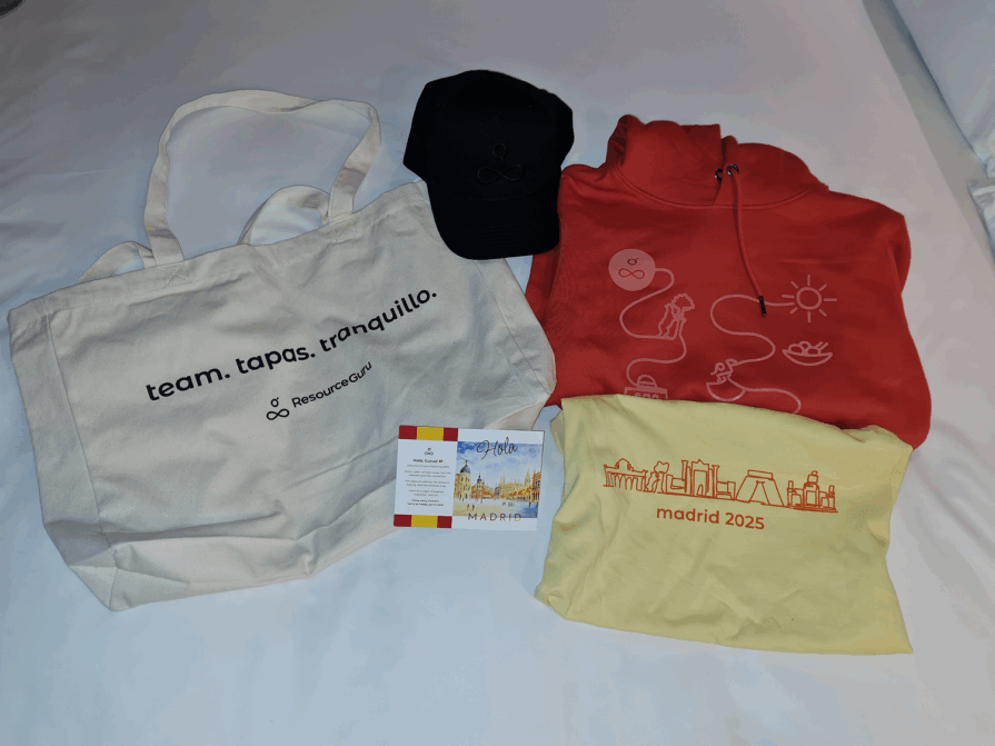 Merch from Guru Gathering 2025 including a sweater, t-shirt, tote, cap, and postcard.