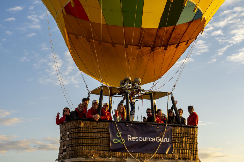 Some of Team Guru in a hot air balloon basket with a Resource Guru banner strung over the side.