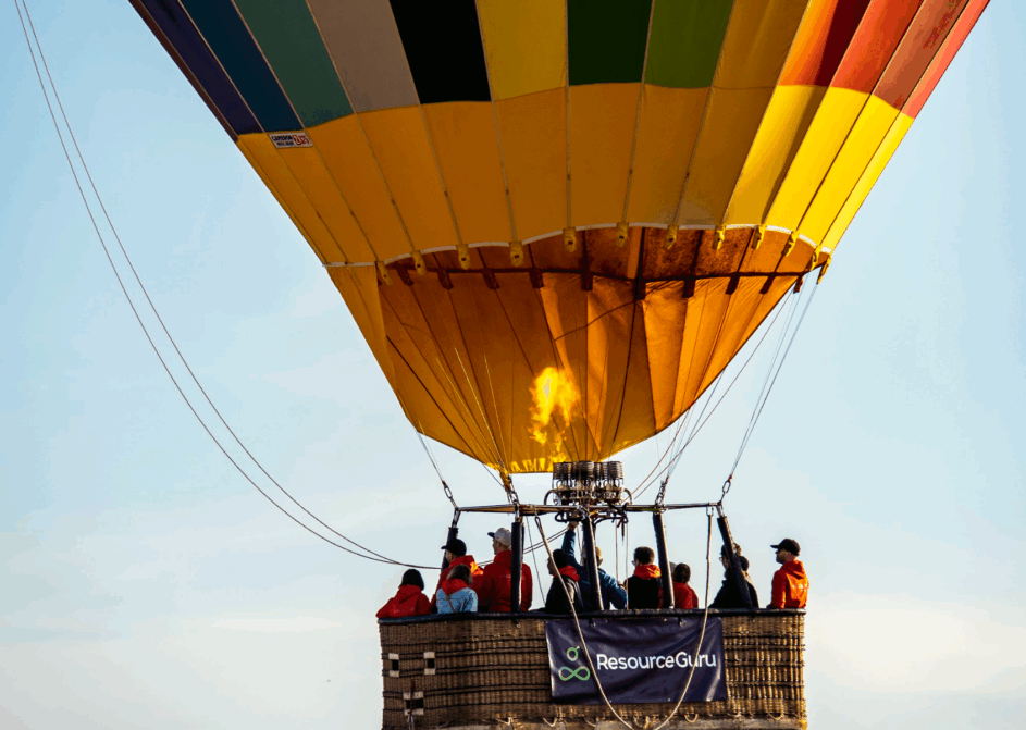 Resource Guru staff on a hot air balloon ride with a Resource Guru banner strung over the side of the basket.